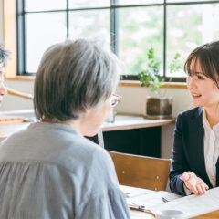 葬儀社スタッフと相談者が資料を見ながら話し合っている様子
