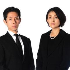 喪服を着た夫婦が静かに立つ様子