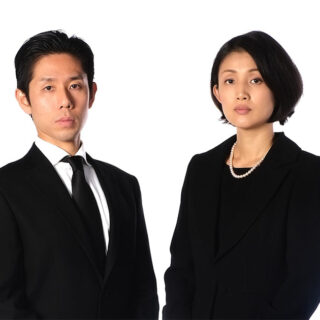 喪服を着た夫婦が静かに立つ様子