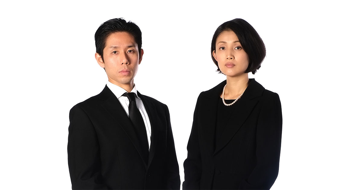 喪服を着た夫婦が静かに立つ様子